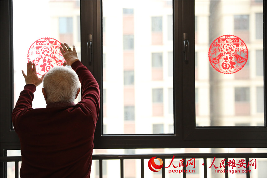 圖為回遷居民正在為新房貼上窗花。人民網 楊華龍攝