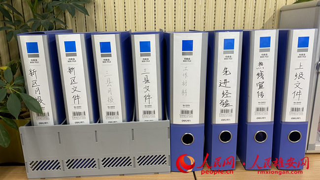 雄安新區“12345”政務服務便民熱線辦公區內擺放的各種資料。人民網 劉師豪攝