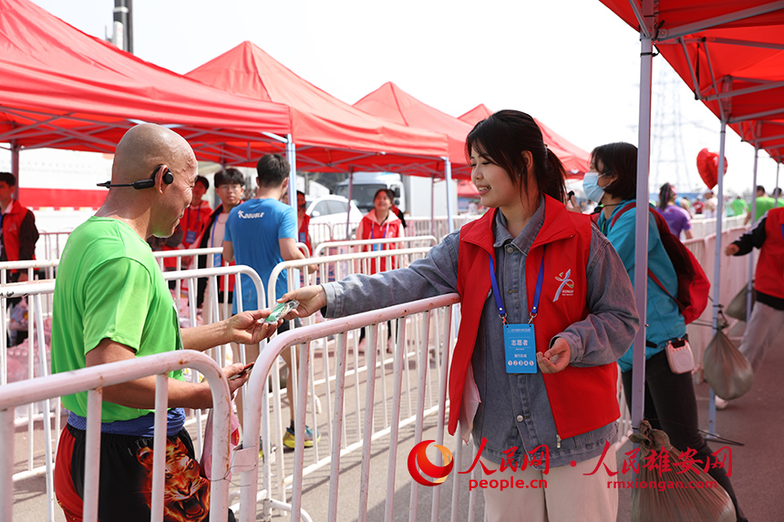 2023雄安半程馬拉松現場，志愿者們為參賽完的選手發放獎牌和補給物資。人民網 李兆民攝