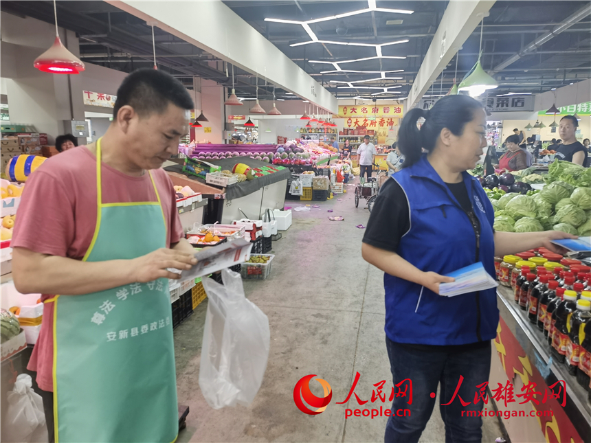 普法活動進市場。安新縣委政法委供圖