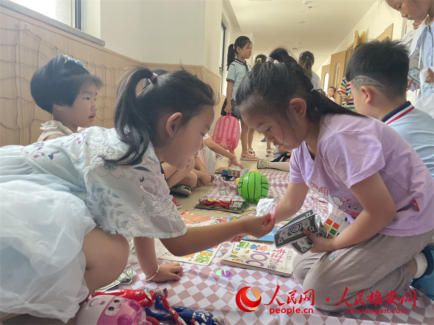 圖為“集市行樂”活動中，學生用“悅容幣”進行交易。雄安容和悅容幼兒園供圖