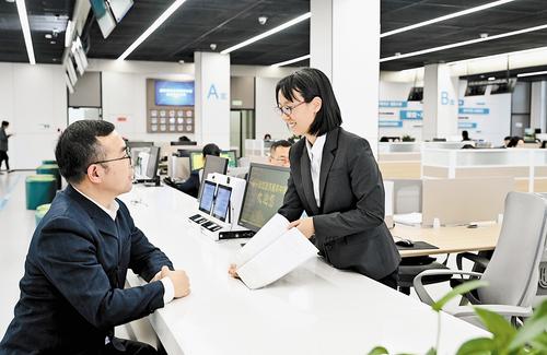 11月14日，雄安新區政務服務中心投資建設項目服務區綜合受理窗口，雄安新區建設和交通管理局工作人員張雅然（右）為辦事群眾解疑答惑。 本報記者 劉光昱攝