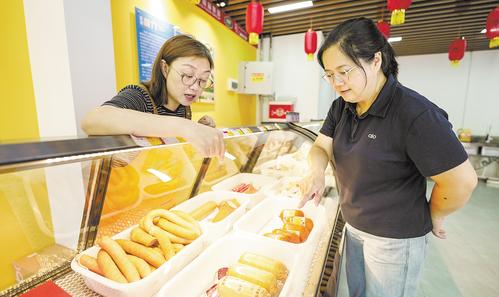 7月11日，位于雄安·老字號商業街的中華老字號天津“迎賓”牌肉制品門店內，顧客正在挑選火腿。本報見習記者 李暢攝