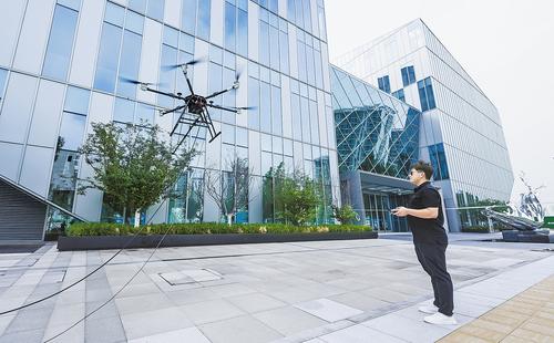 7月16日，在雄安高新區未來科創城“智慧之芯”系列辦公樓下，專業飛手操控六軸重載無人機進行玻璃幕墻清潔作業。 本報見習記者 李暢攝